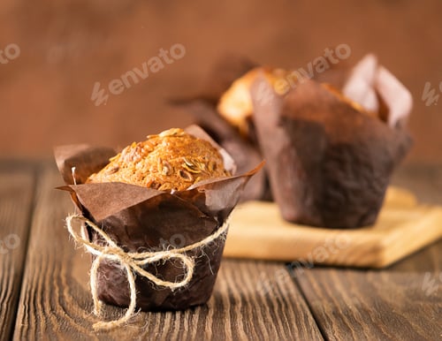 Preview: Muffins with wheat flakes in brown paper packaging close-up wooden background. Healthy vegan dessert