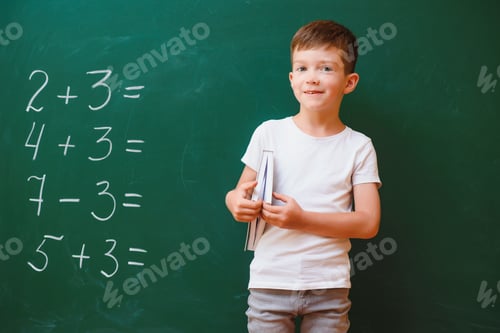 Preview: Funny schoolboy near the green school board in the classroom. Elementary school. Back to school.