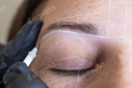 Preview: Close-up of microblading process: art of eyebrow tattooing. With gloved hands, skilled practitioner