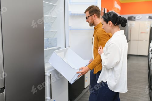 Preview: Young couple, satisfied customers choosing fridge in appliances store