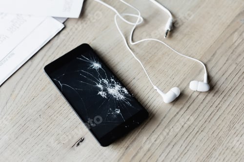 Preview: Close up view of smashed cellphone with earphones and paper sheets on wooden background
