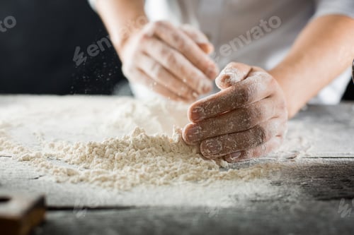 Preview: Male chef hands knead the dough with flour on the kitchen table