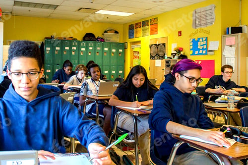 Preview: Class of teenage boys and girls doing schoolwork at classroom desks