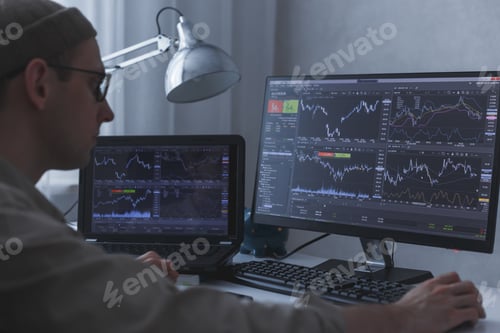 Preview: Thoughtful serious trader broker analyzing stock market graphs at pc and laptop