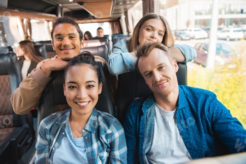 Preview: portrait of happy multicultural friends looking at camera during trip on travel bus