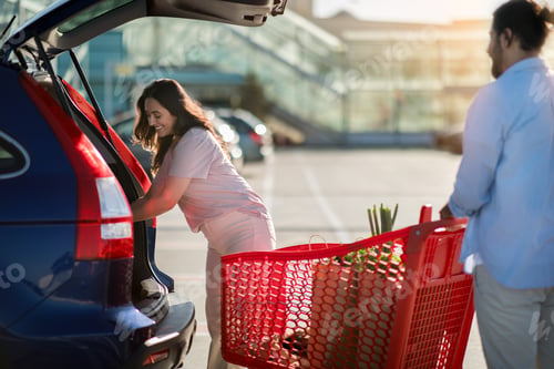 Preview: Woman loading car, man with cart outdoors