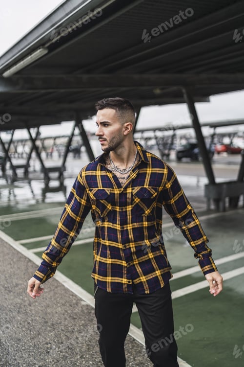 Preview: Man with stylish shirt poses in a parking garage