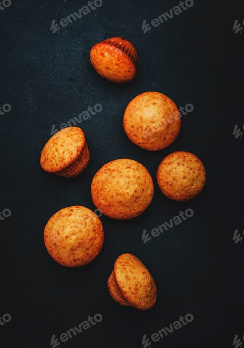 Preview: Appetizing orange muffins or cupcakes on black table background, winter homemade pastries, top view