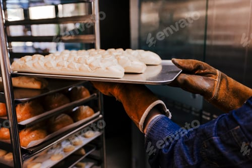 Preview: close up view of woman holding holding rack of rolls in a bakery.