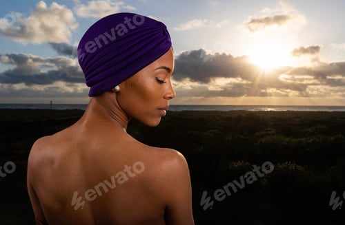 Preview: African American woman outside with ocean beach view wearing purple turban
