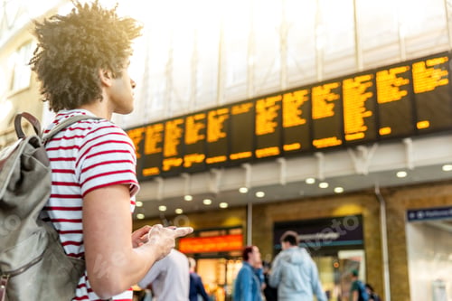 Preview: Man waiting for train and using phone at train station in London