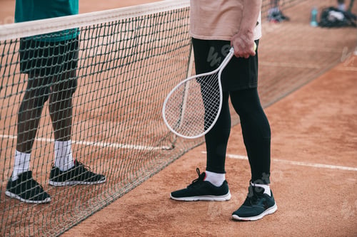 Preview: cropped shot of interracial friends with tennis racquet standing near net