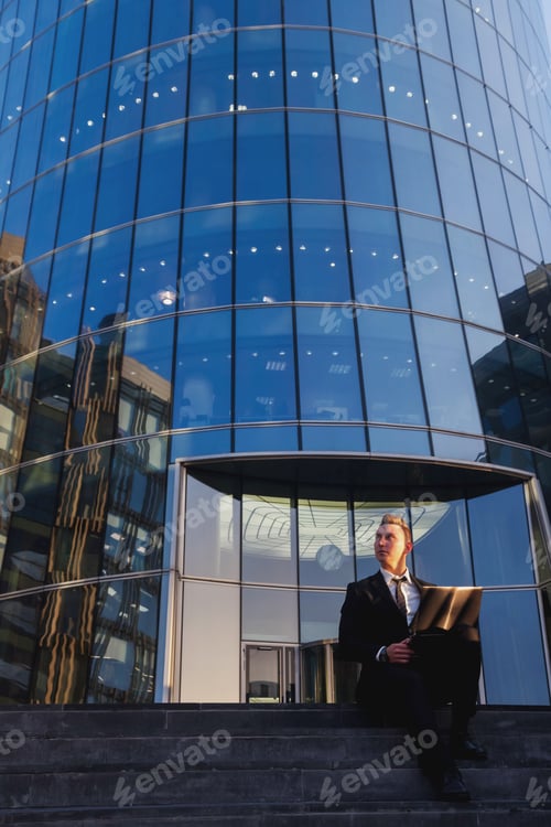 Preview: Young man businessman in style wear clothes, suit sitting on steps with laptop