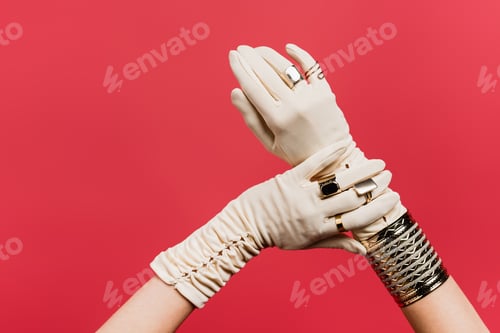 Preview: partial view of woman in gloves with rings and bracelet isolated on red
