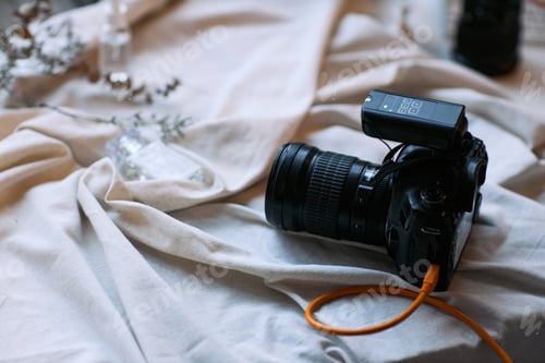 Preview: Professional Digital Camera with Flash Trigger Resting on Fabric Surface