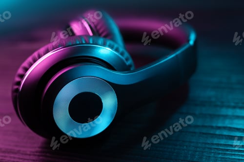 Preview: Black headphone on dark wooden background. Stylish wireless headset in neon light.