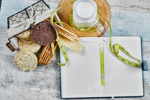 Preview: Basket of biscuits and a jar of milk on a marble table with a notebook and pen