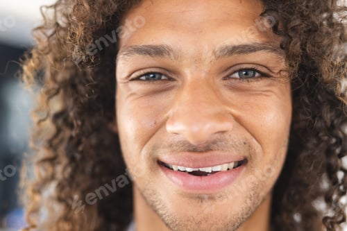 Preview: A young biracial man with curly hair smiles warmly at the camera
