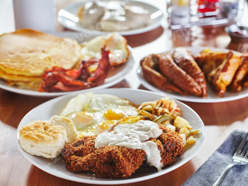 Preview: chicken fried steak covered in gravy with sunny side up eggs and breakfast foods