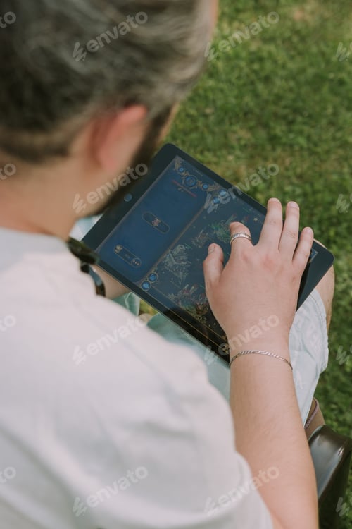 Preview: Man playing a game on a tablet in the garden