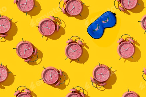 Preview: Top view of creative pattern made of pink alarm clocks and sleeping mask on a yellow background