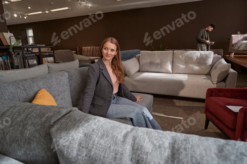 Preview: Smiling tranquil female shopper choosing new couch