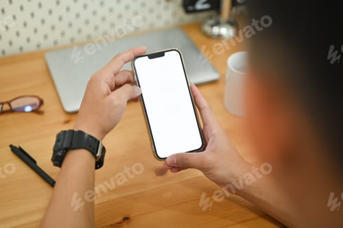 Preview: Close up male hands using smartphone at working desk searching data or chatting online