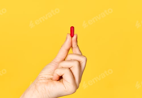 Preview: Red Pill Held Between Two Fingers