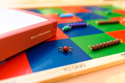 Preview: Spine of a book about Maria Montessori on a board of educational teaching material.