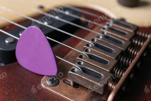 Preview: Closeup view of electric guitar, focus on bridge with strings and plectrum