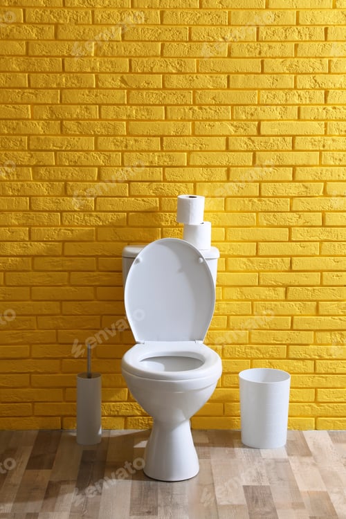 Preview: Simple bathroom interior with toilet bowl near yellow brick wall indoors. Home design