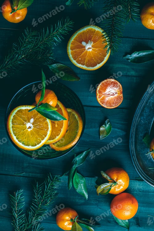 Preview: Tangerines with green leaves on a green wooden table in a rustic style surrounded by spruce branches
