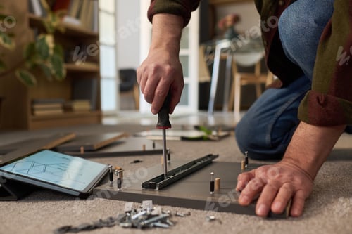 Preview: Young Adult Man Assembling Furniture Using Screwdriver Indoors