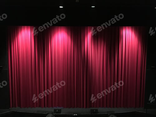 Preview: Closed Red theater curtains on stage with lights from above partially lighting the curtains