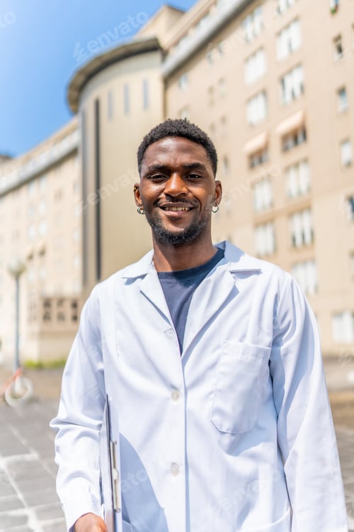 Preview: Cheerful african doctor smiling at camera outside the hospital