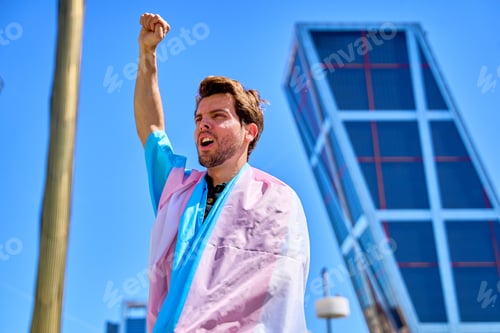 Preview: man with transgender flag raises fist in sign of struggle