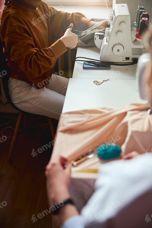 Preview: Person near window reaching to thread with crafting scissors