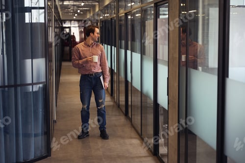 Preview: Smiling company employee with laptop in hallway during coffee break