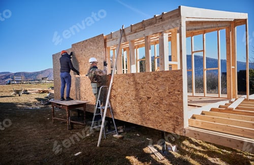 Preview: Man worker building wooden frame house, mounting wooden OSB board.