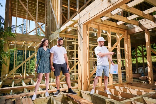 Preview: Man designer with plan showing the process of constructing wooden framed house.