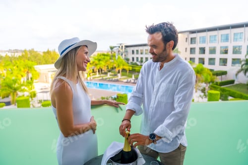 Preview: Couple opening a bottle of champagne in an hotel terrace