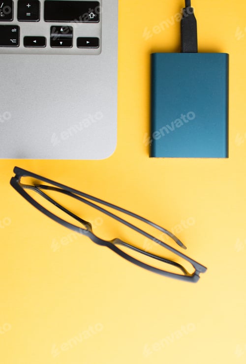Preview: Vertical shot of a notebook edge with a power bank and eyeglasses