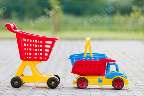 Preview: Bright plastic colorful toys for children outdoors on sunny summer day. Car truck, basket and