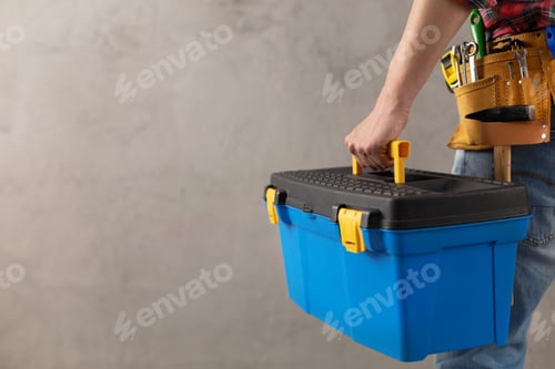 Preview: Man worker holding toolbox and tool belt near wall. Male hand and construction tools