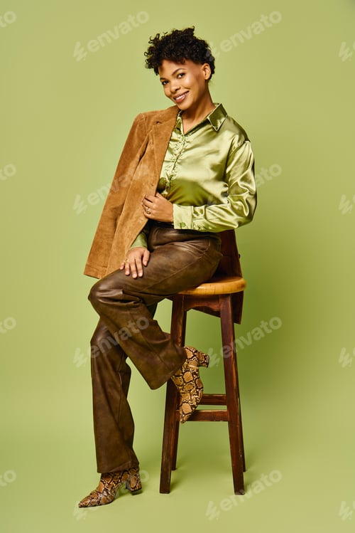 Preview: Fashionable african american woman showcasing modern style against a vibrant green backdrop