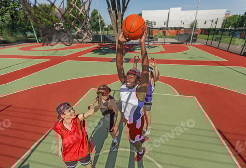 Preview: Black basketball player jumping to score goal and his team at outdoor court