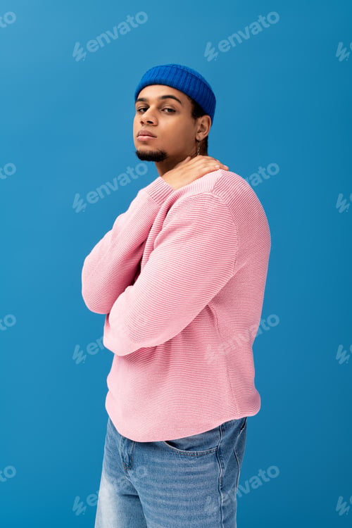 Preview: Stylish young man posing against a vibrant blue backdrop in trendy casual attire