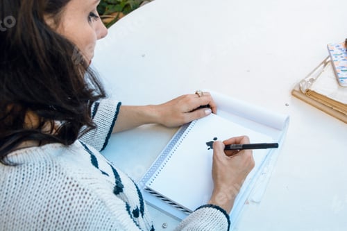 Preview: rear view of female designer working, drawing with marker on white leaf notebook