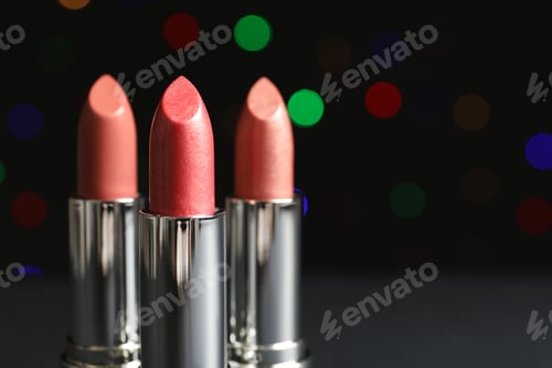 Preview: Different lipsticks on table against blurred lights. Space for text