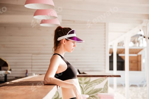 Preview: Young sports woman resting after workout at the beach cafe